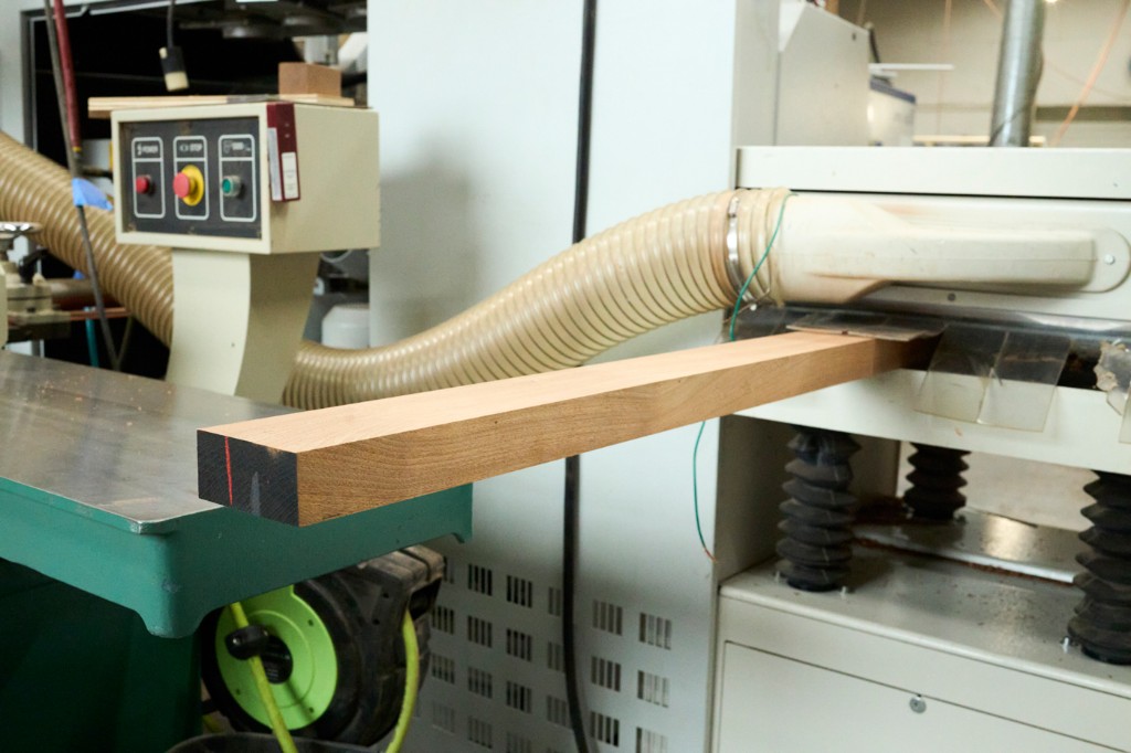 Hardwood stock running through industrial planer in the mill