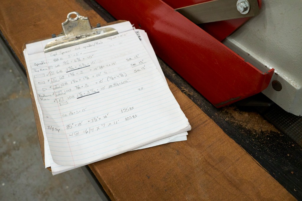 Handwritten cut list and material notes on a clipboard at the bench