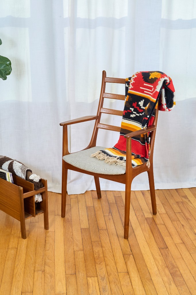 Chair with blanket, magazine rack, and layered textiles in frame